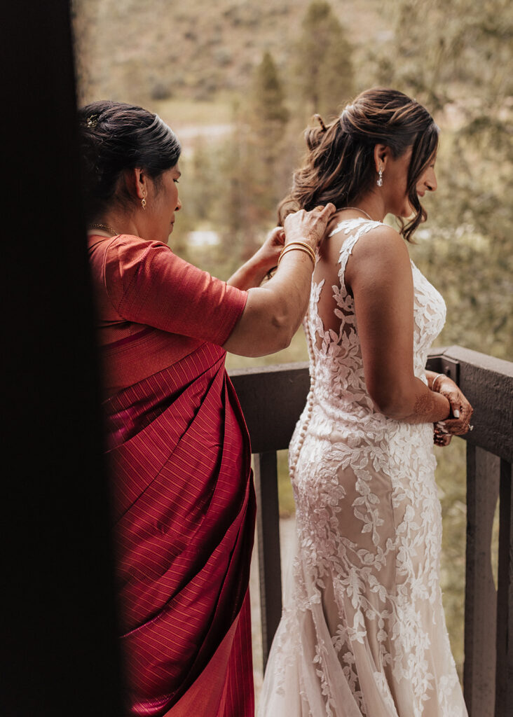 Mother helping her daughter into wedding dress in Vail, CO.