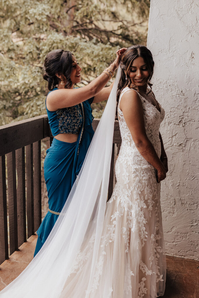 Bridesmaid helping bride put on wedding veil in Vail, CO.