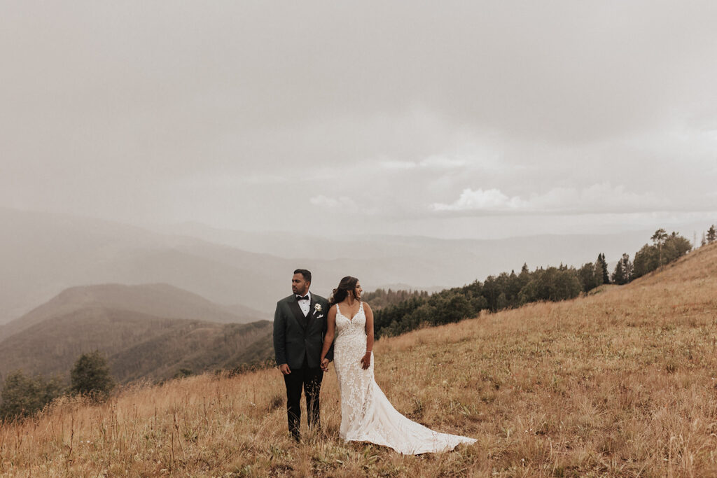 Bride and groom holding hands atop Vail Mountain in CO.