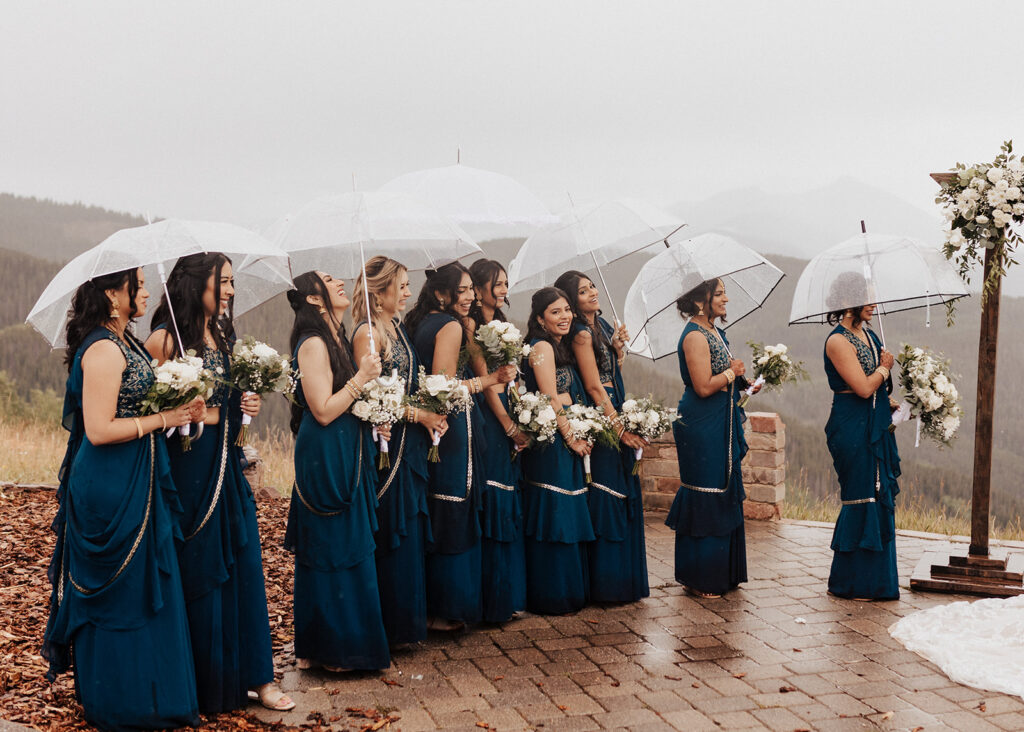 Bridesmaids under umbrellas during rainy wedding ceremony in Vail, CO.