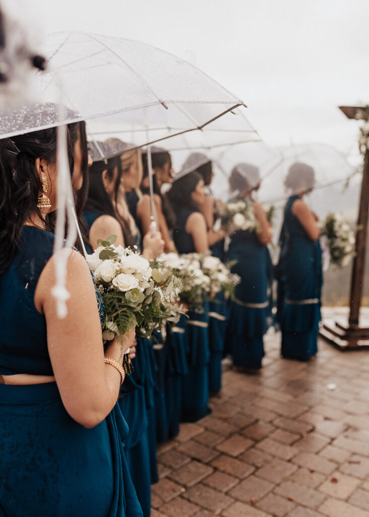 Bridesmaids under umbrellas during rainy wedding ceremony in Vail, CO.