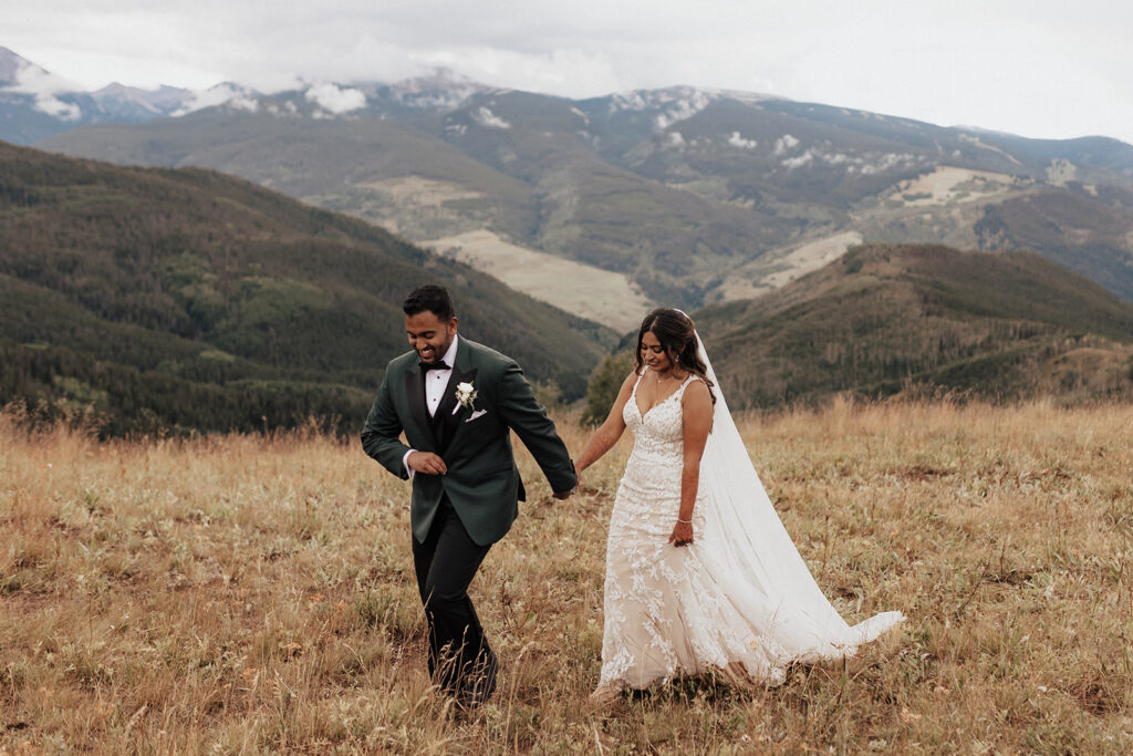 Bride and groom holding hands as they walk atop Vail Mountain in Colorado.