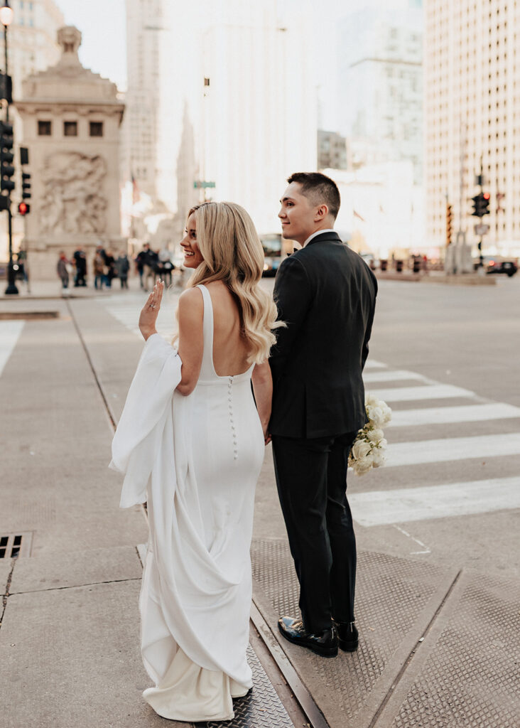 Bride and groom wait to cross Michigan Avenue in Chicago, IL