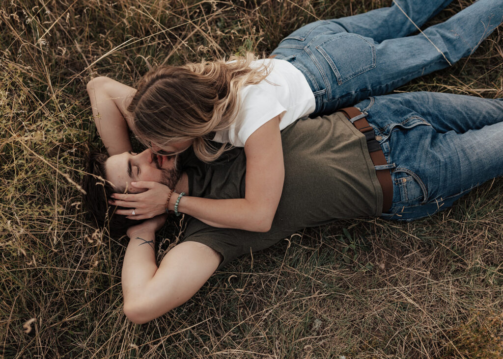 Engaged couple laying in field in Boulder, CO