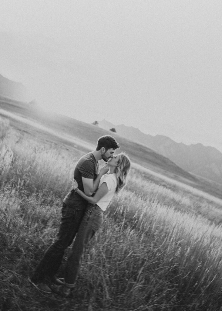 Engaged couple kissing in open field in Boulder, CO