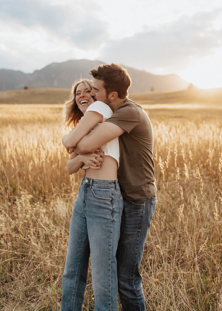 Engaged couple laughing in open field in Boulder, CO