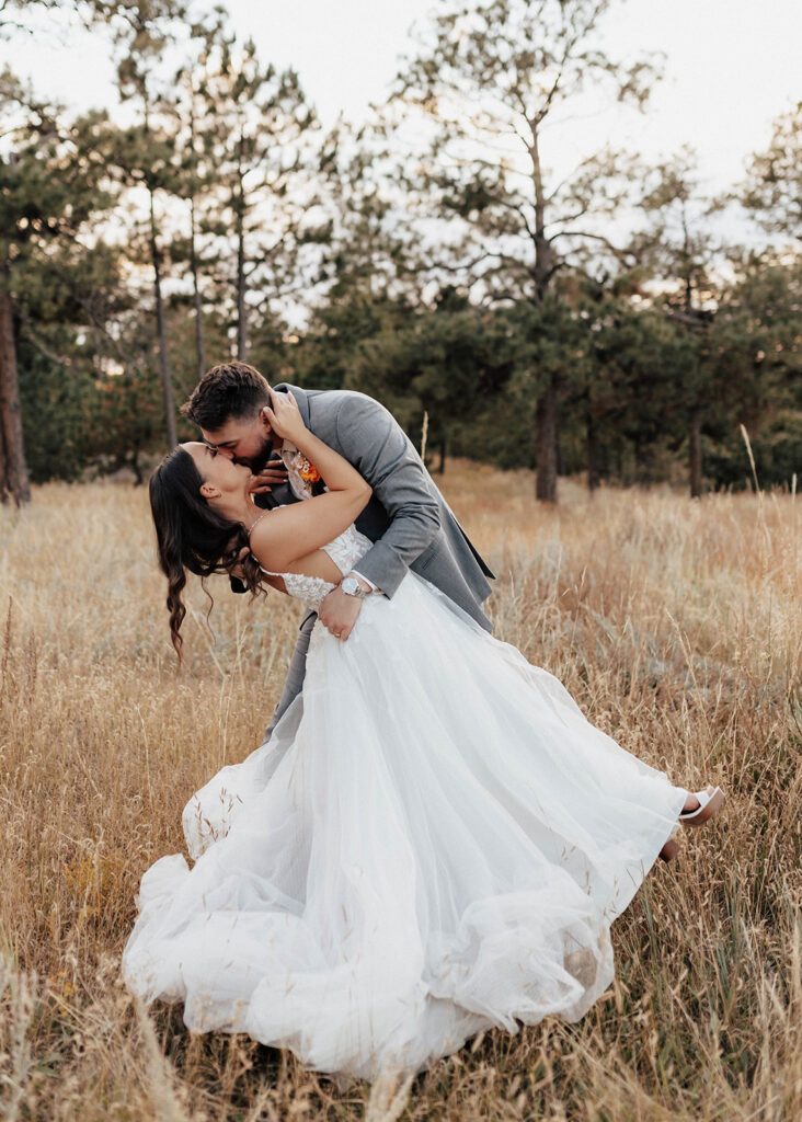 Bride and groom kissing in a golden field in Colorado Springs, CO