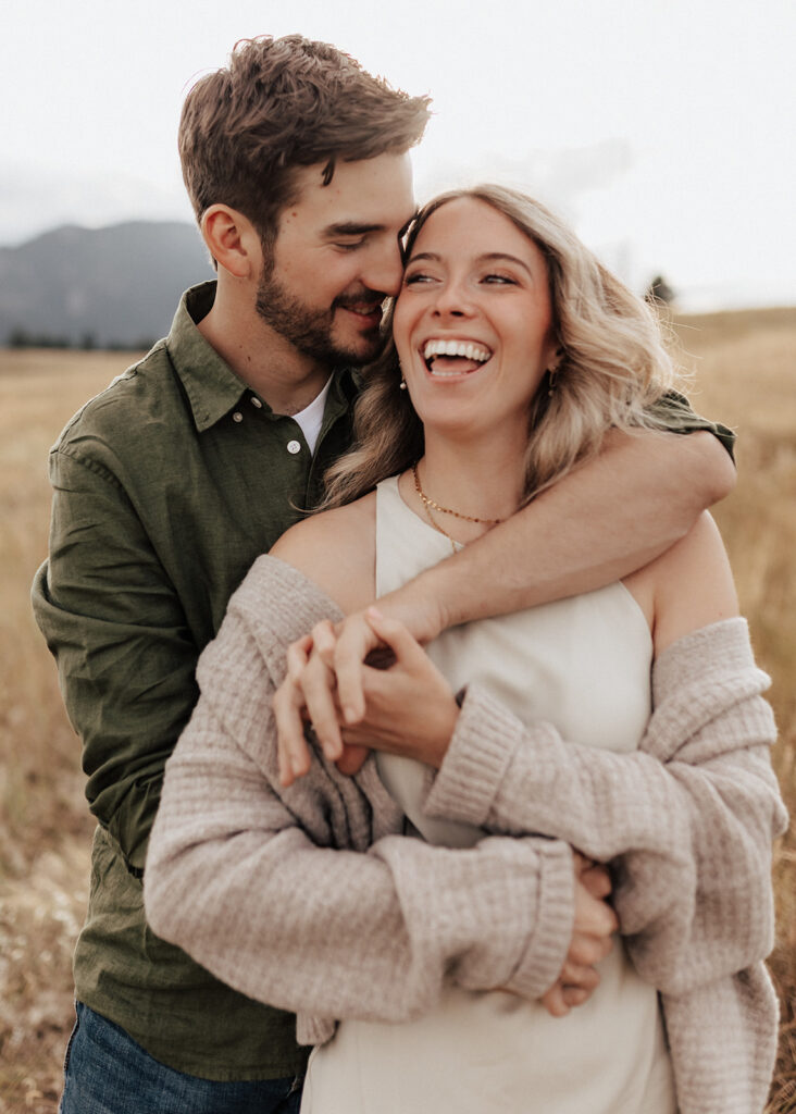 Engaged couple laughing in a golden field in Boulder, CO