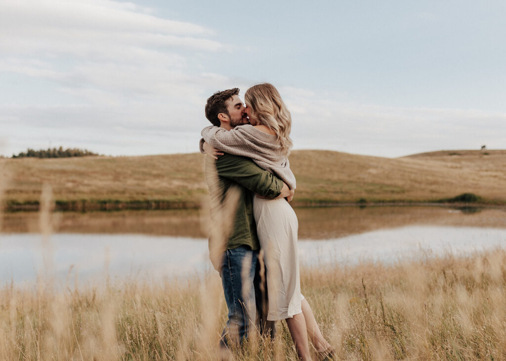 Engaged couple kissing in a golden field in Boulder, CO