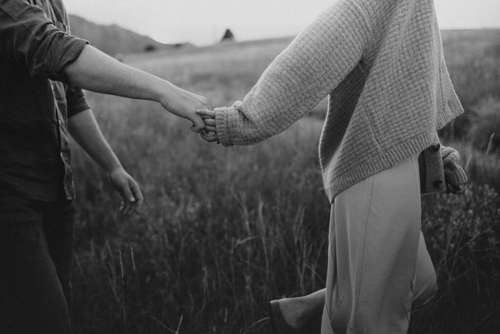 Engaged couple holding hands in a field in Colorado