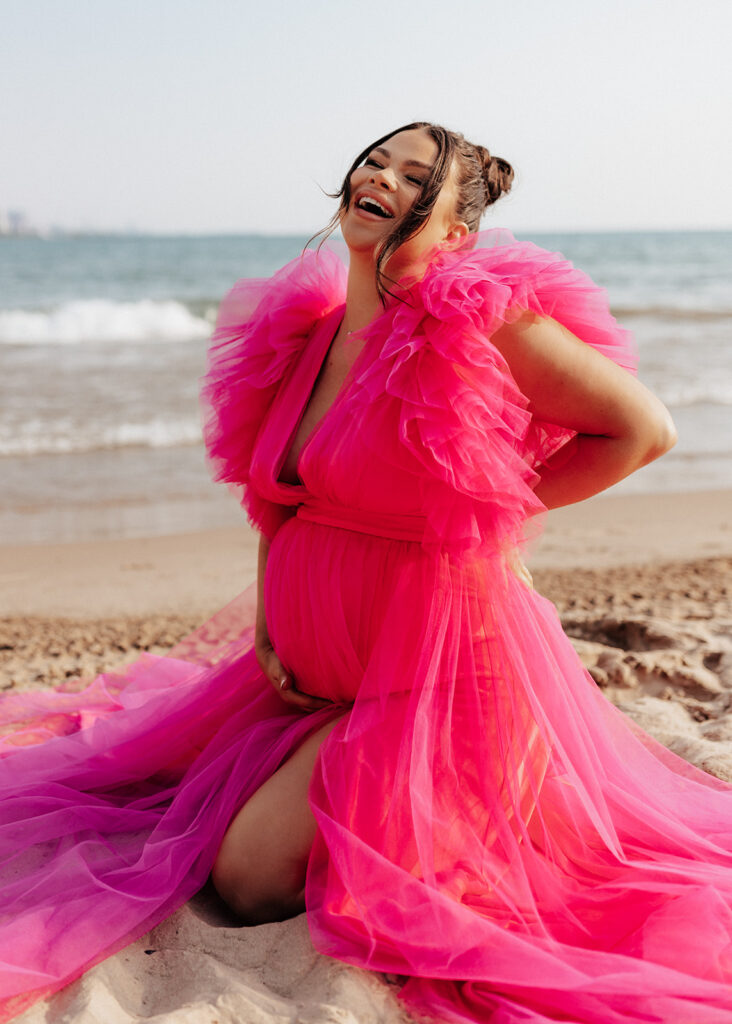 Pregnant woman laughing on the beach in Chicago.