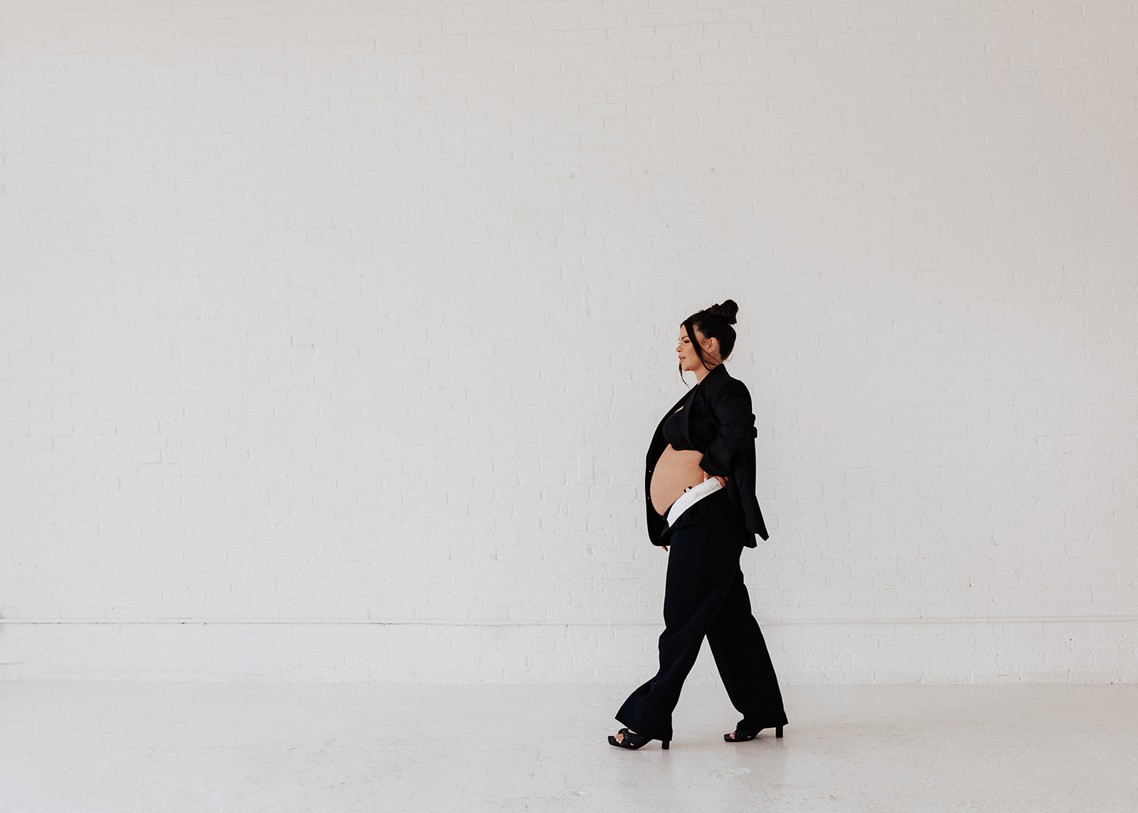 Pregnant woman walking away during studio maternity photoshoot.